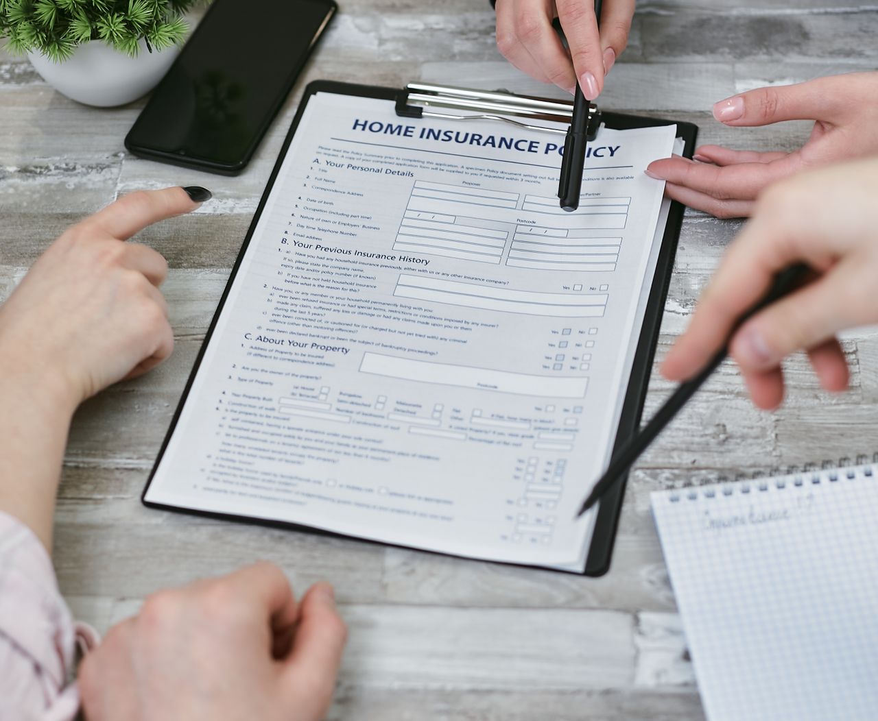 The Art of Drawing Readers In: Your attractive post title goes here Three individuals collaborating on a home insurance policy document. Elements include a clipboard, notes, and pointing hands.
