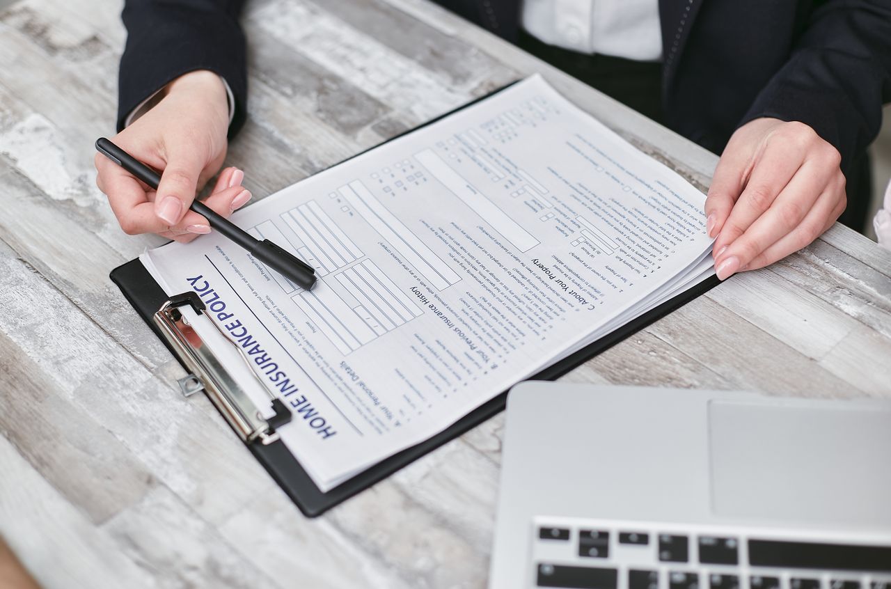 Mastering the First Impression: Your intriguing post title goes here Close-up of hands reviewing a home insurance policy, emphasizing professionalism and finance.